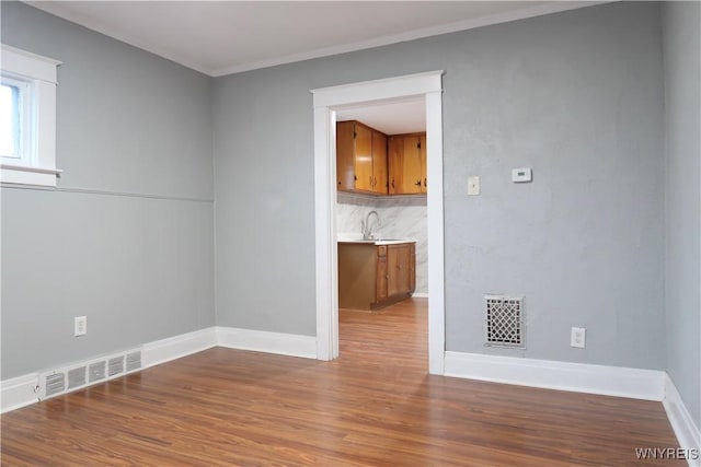 spare room with hardwood / wood-style flooring, crown molding, and sink