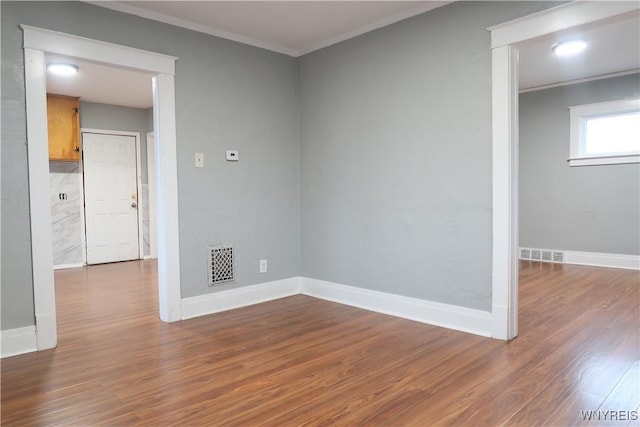 spare room featuring crown molding and hardwood / wood-style floors