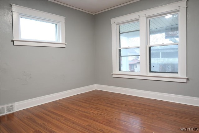 empty room featuring wood-type flooring and ornamental molding