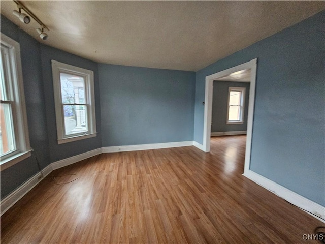 spare room featuring wood-type flooring, a textured ceiling, and track lighting