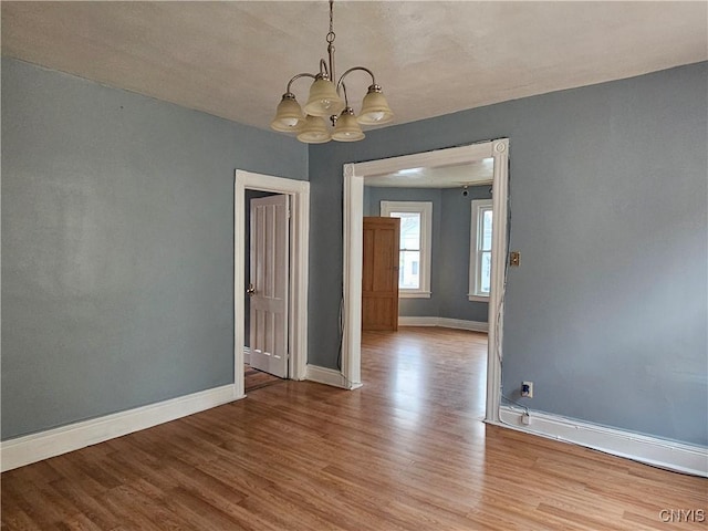 spare room featuring light hardwood / wood-style flooring and a notable chandelier