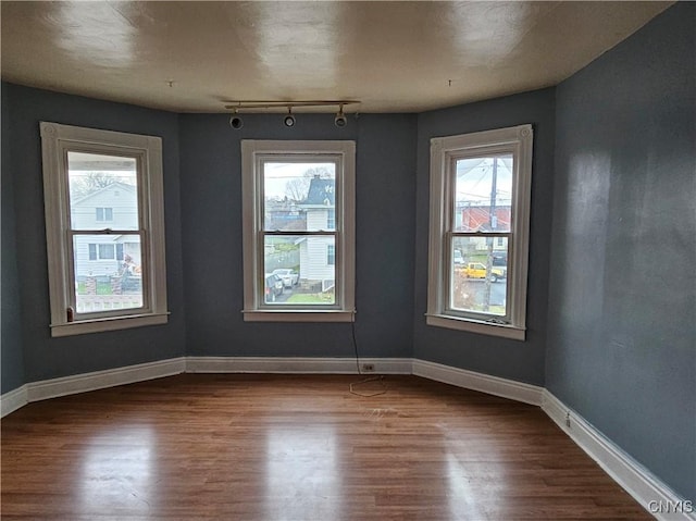 empty room with hardwood / wood-style floors and track lighting