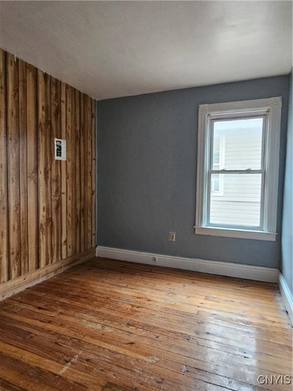 empty room with light hardwood / wood-style flooring and wooden walls