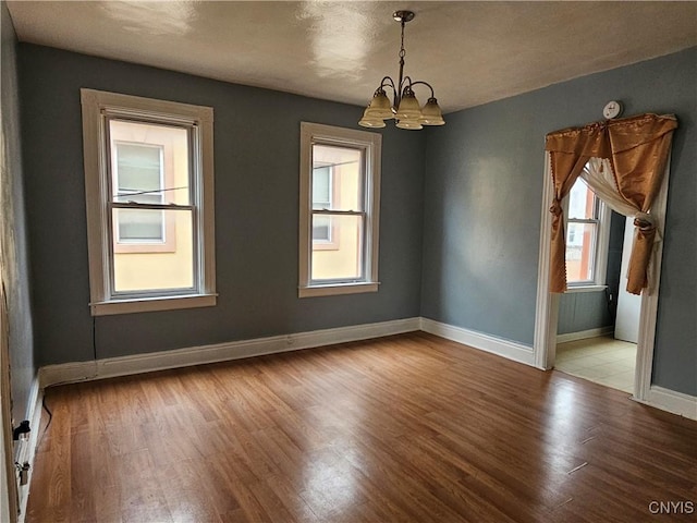 unfurnished room featuring hardwood / wood-style flooring and an inviting chandelier