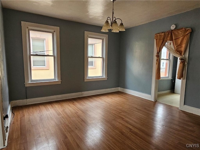 unfurnished room with light wood-type flooring and an inviting chandelier