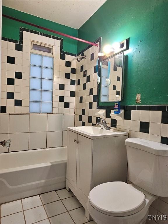 full bathroom featuring tile patterned flooring,  shower combination, toilet, and tile walls