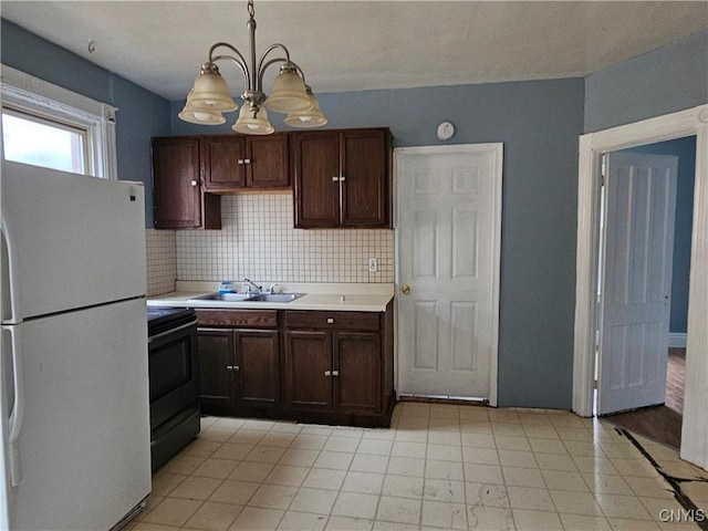 kitchen with backsplash, sink, white refrigerator, black range with electric stovetop, and hanging light fixtures