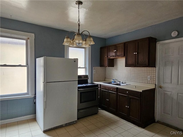 kitchen with sink, white refrigerator, a chandelier, pendant lighting, and stainless steel electric stove