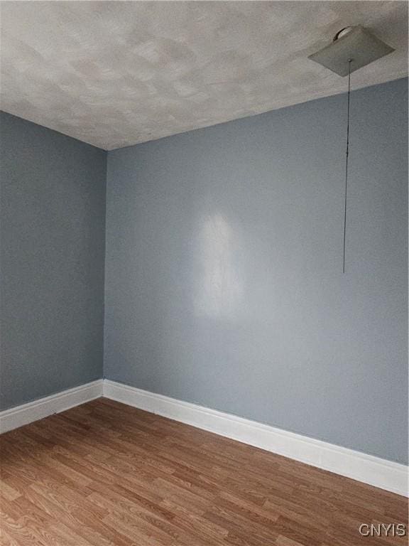 unfurnished room with wood-type flooring and a textured ceiling