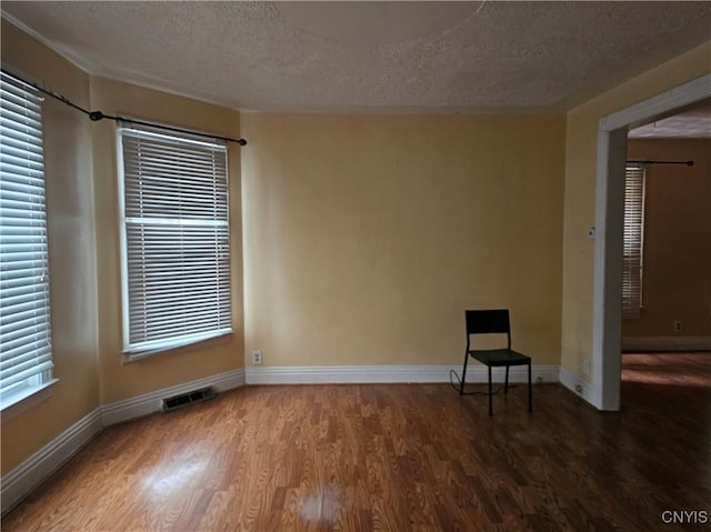 empty room with dark wood-type flooring and a textured ceiling