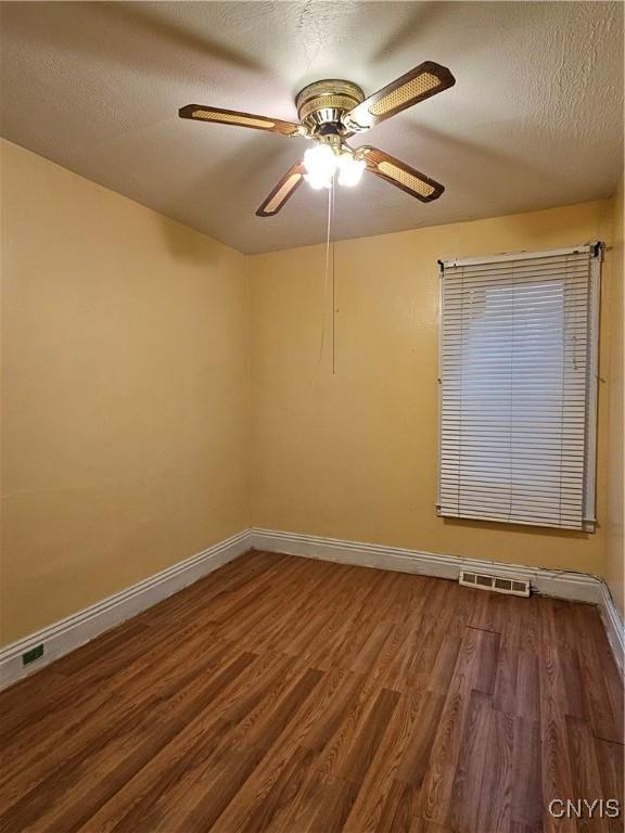 unfurnished room featuring a textured ceiling, dark hardwood / wood-style flooring, and ceiling fan