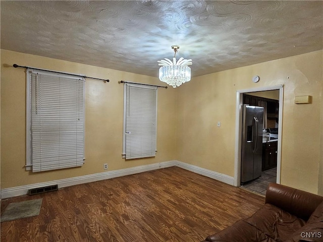 spare room with wood-type flooring and a notable chandelier