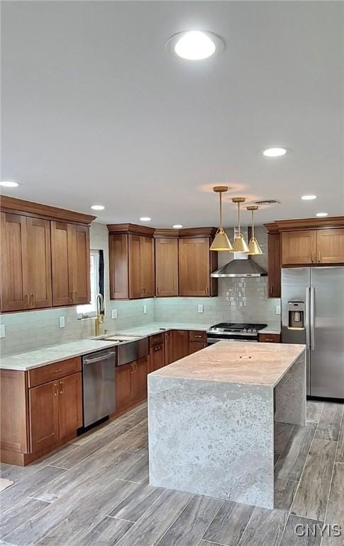 kitchen with sink, hanging light fixtures, light wood-type flooring, appliances with stainless steel finishes, and a kitchen island