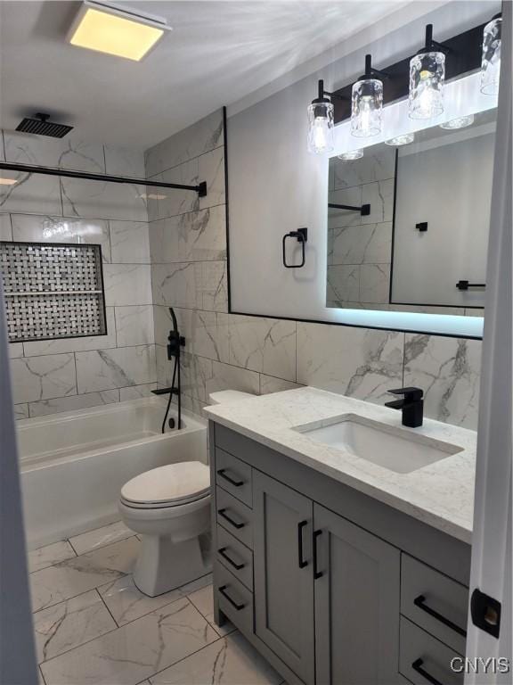 full bathroom with vanity, tiled shower / bath combo, toilet, and tile walls