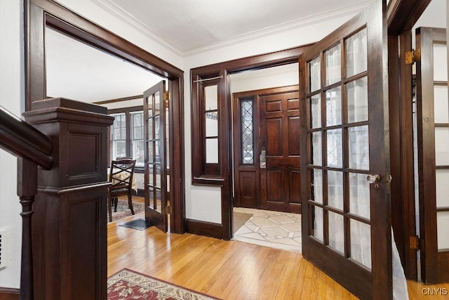 foyer entrance with crown molding, light hardwood / wood-style flooring, and french doors