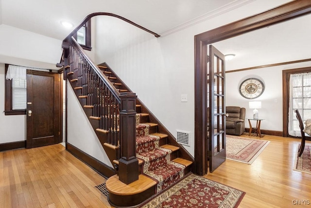 stairs featuring hardwood / wood-style floors and ornamental molding