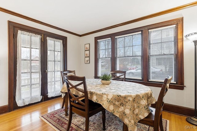 dining room featuring light wood-type flooring, crown molding, and french doors