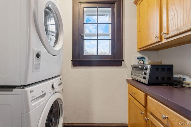 laundry room featuring stacked washer / drying machine and cabinets