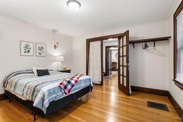 bedroom with crown molding, french doors, and hardwood / wood-style flooring