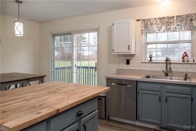 kitchen with stainless steel dishwasher, a healthy amount of sunlight, sink, and hanging light fixtures