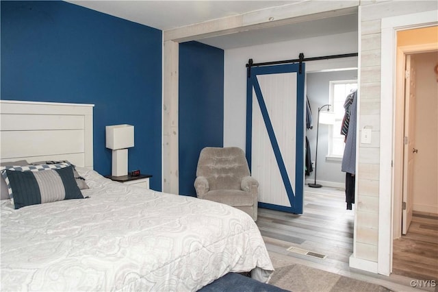 bedroom featuring hardwood / wood-style flooring, a barn door, and a closet