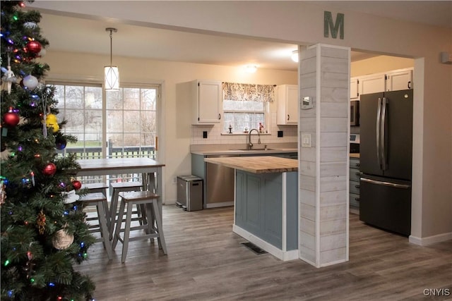 kitchen with pendant lighting, sink, appliances with stainless steel finishes, tasteful backsplash, and white cabinetry