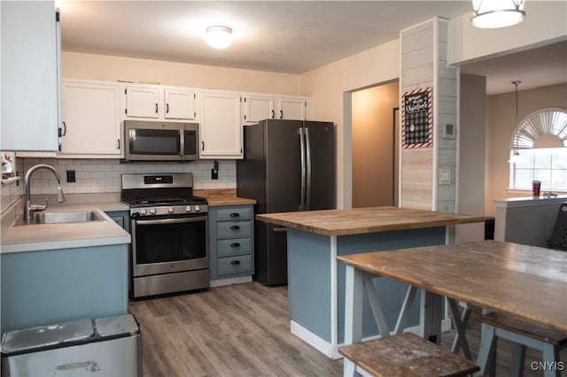 kitchen with appliances with stainless steel finishes, white cabinetry, hanging light fixtures, and sink