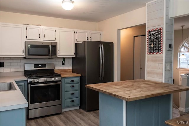 kitchen featuring white cabinets, wood counters, hardwood / wood-style floors, and appliances with stainless steel finishes