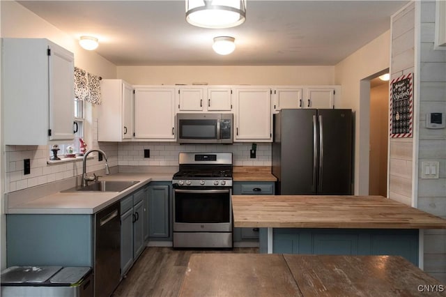 kitchen with backsplash, stainless steel appliances, white cabinetry, and sink