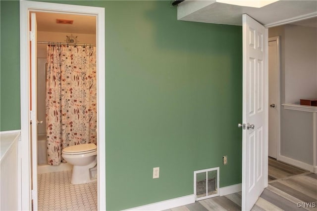 bathroom featuring wood-type flooring, shower / tub combo, and toilet