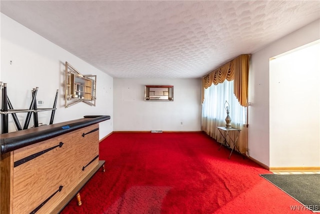 misc room featuring a textured ceiling and dark colored carpet