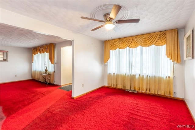 empty room with carpet, ceiling fan, a textured ceiling, and a wealth of natural light