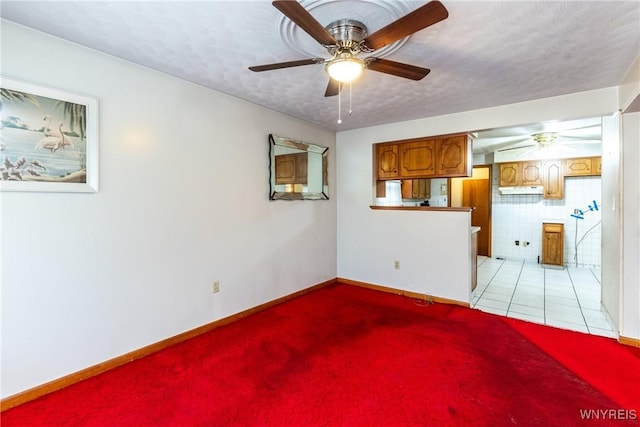 unfurnished living room with ceiling fan, light tile patterned flooring, and a textured ceiling