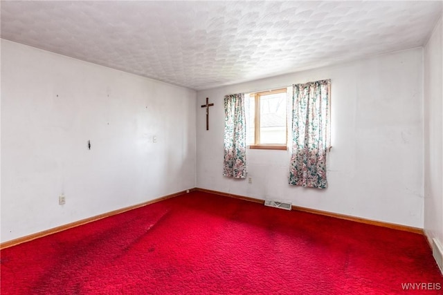 empty room with a textured ceiling and carpet floors