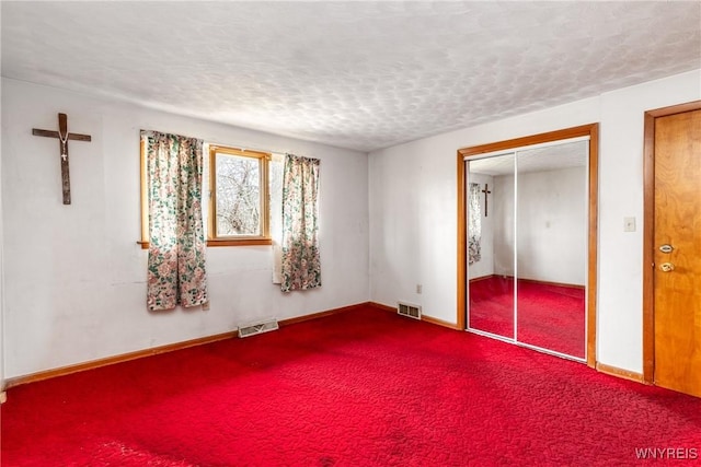 carpeted empty room featuring a textured ceiling