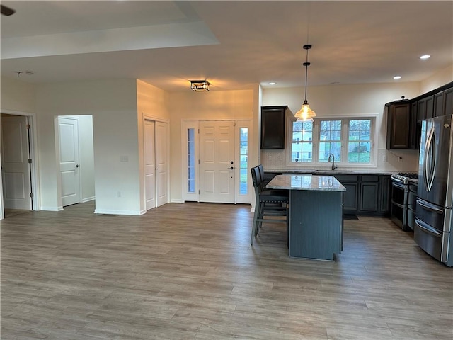 kitchen featuring pendant lighting, a center island, backsplash, light stone countertops, and appliances with stainless steel finishes