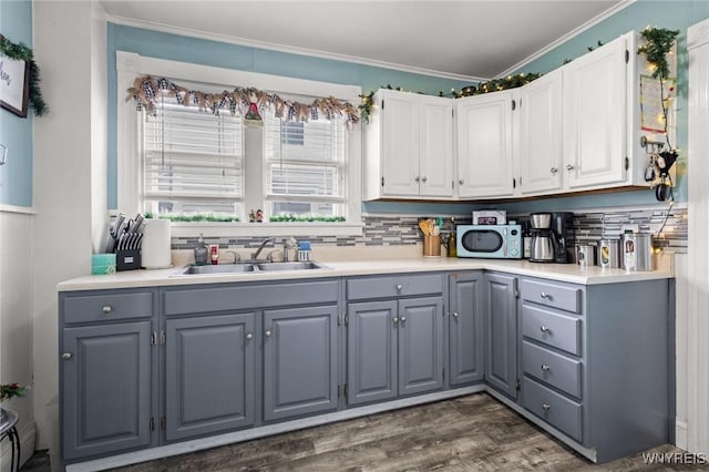 kitchen featuring white cabinets, gray cabinetry, ornamental molding, and sink