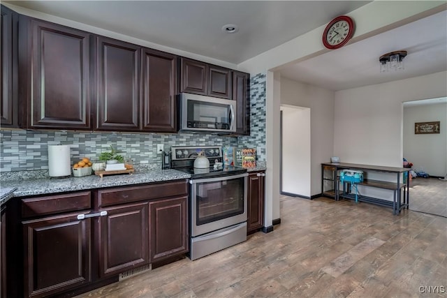 kitchen with decorative backsplash, light hardwood / wood-style floors, dark brown cabinetry, and appliances with stainless steel finishes