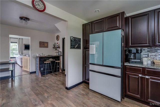 kitchen featuring hardwood / wood-style floors, dark brown cabinets, white fridge, and decorative backsplash