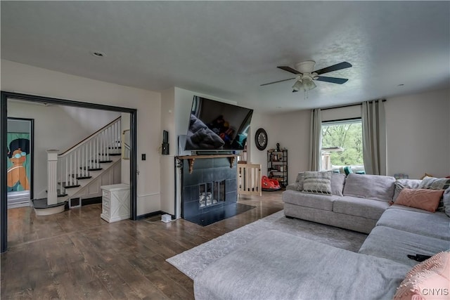 living room with a tile fireplace, dark hardwood / wood-style flooring, and ceiling fan