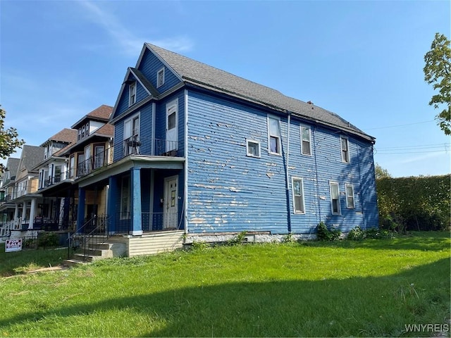 view of side of property with a lawn and a balcony