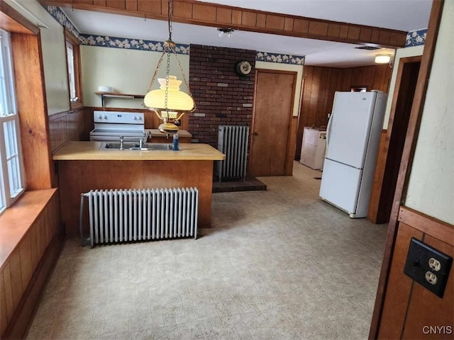 kitchen with radiator, wooden walls, kitchen peninsula, and white refrigerator