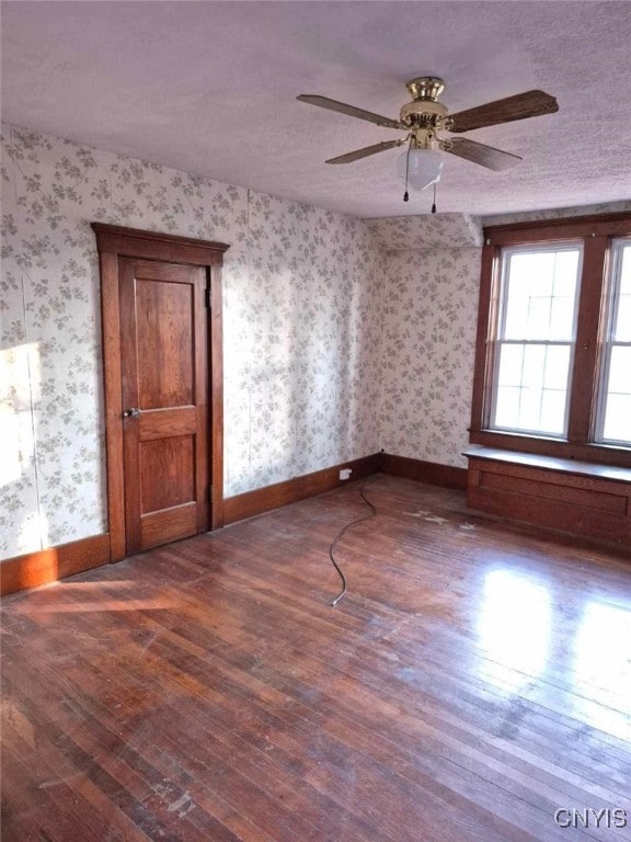 empty room featuring ceiling fan, dark hardwood / wood-style flooring, and a textured ceiling