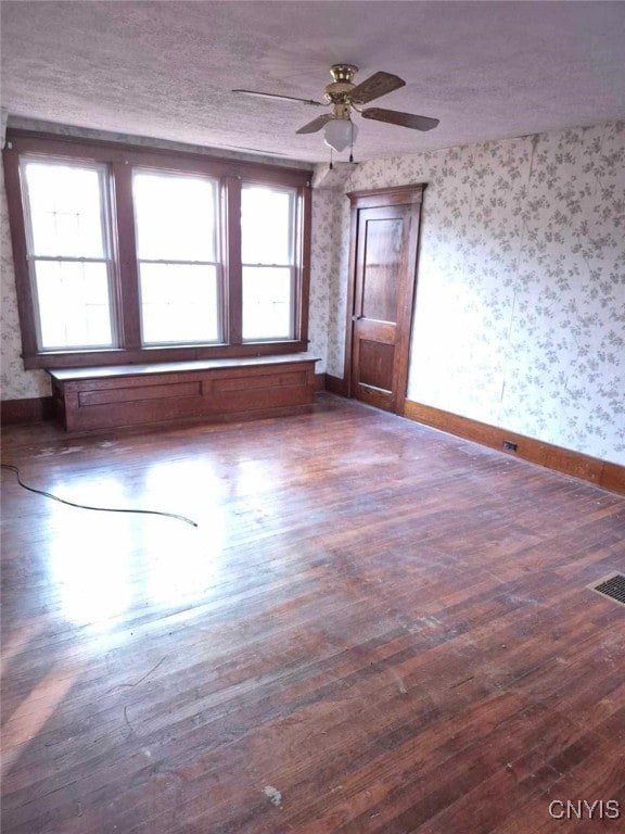 unfurnished room with a textured ceiling, dark hardwood / wood-style floors, and ceiling fan