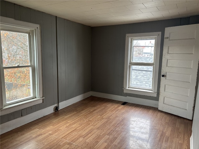 unfurnished room featuring wood walls and light hardwood / wood-style floors