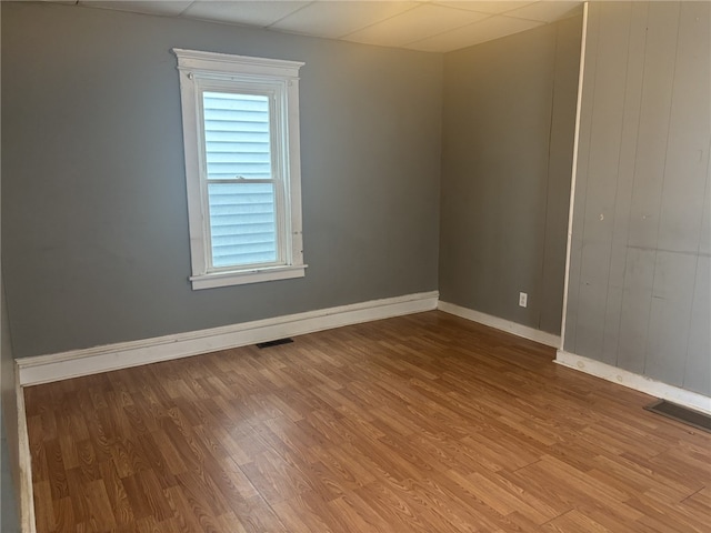 spare room with hardwood / wood-style floors and a drop ceiling