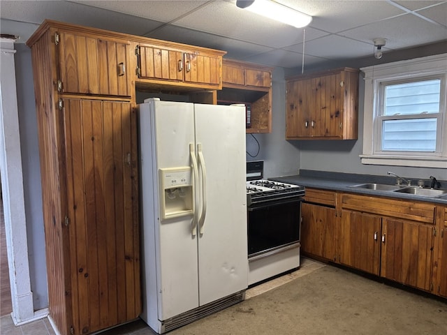 kitchen with a paneled ceiling, white appliances, and sink