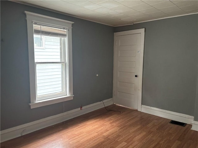 empty room featuring ornamental molding and hardwood / wood-style flooring