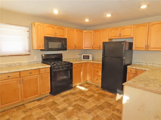 kitchen with black appliances, light stone counters, and light brown cabinetry