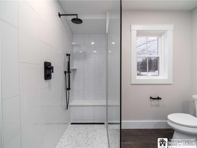 bathroom featuring hardwood / wood-style flooring, toilet, and a tile shower